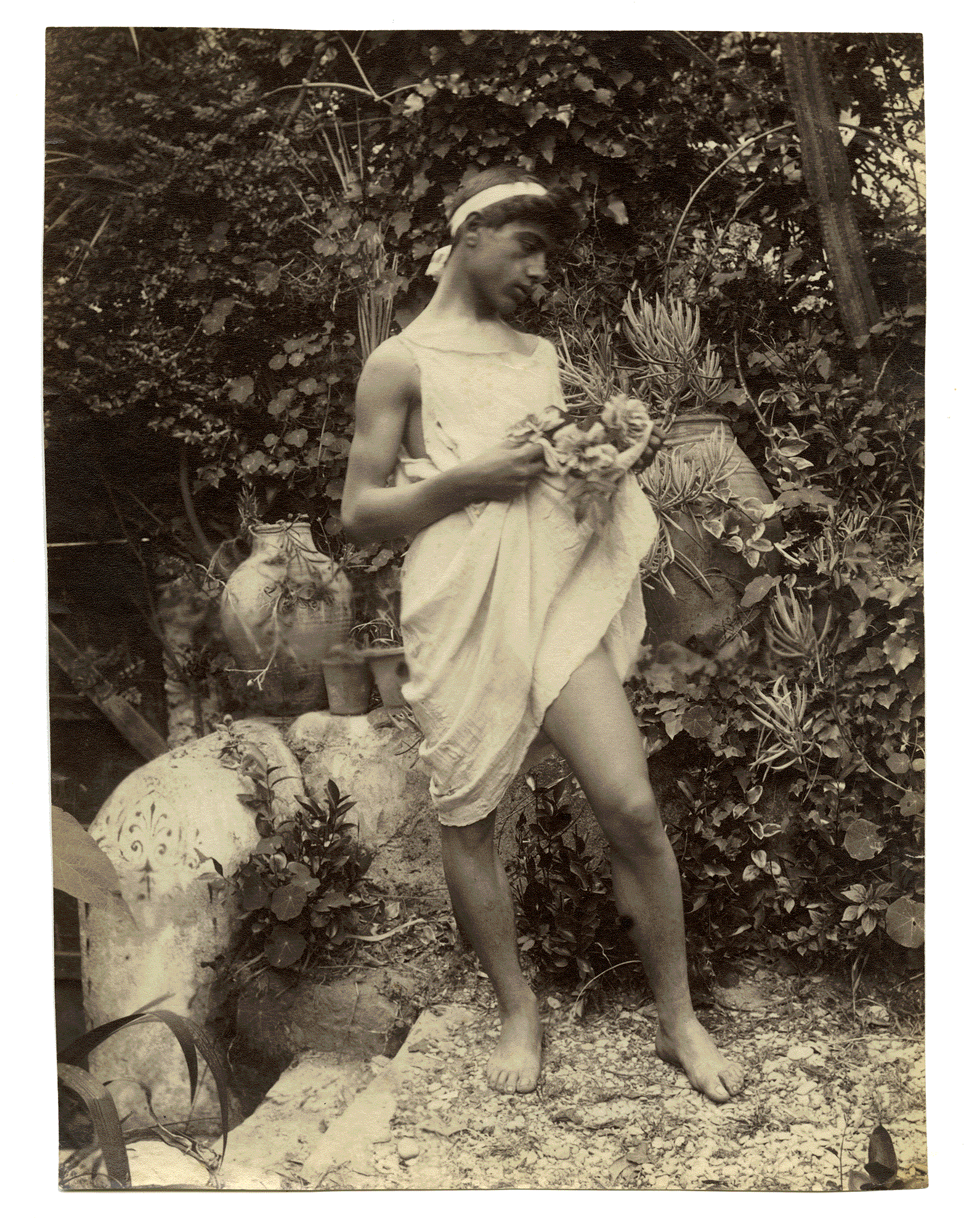 A STANDING BOY DRESSED IN GREEK GARB, IN GLOEDEN’S GARDEN. Wilhelm von Gloeden. Taormina 1902.